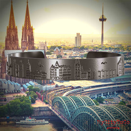 Armreif aus Titan mit Reliefs bekannter Sehenswürdigkeiten der Stadt Köln. Den Hintergrund bildet eine Ansicht der Stadt Koeln.