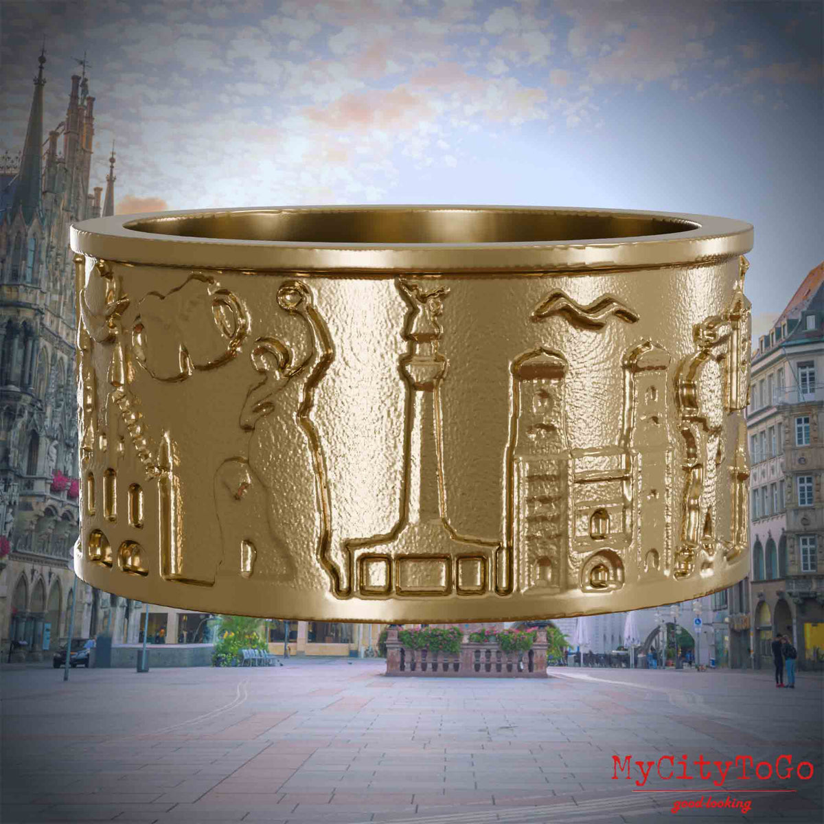 Ring aus vergoldetem Edelstahl mit Reliefs bekannter Sehenswürdigkeiten der Stadt Muenchen. Den Hintergrund bildet eine Ansicht der Stadt Muenchen.