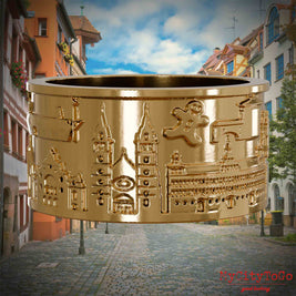 Vergoldeter Ring mit Reliefs bekannter Sehenswürdigkeiten der Stadt Nuernberg. Den Hintergrund bildet eine Ansicht der Stadt  Nuernberg.