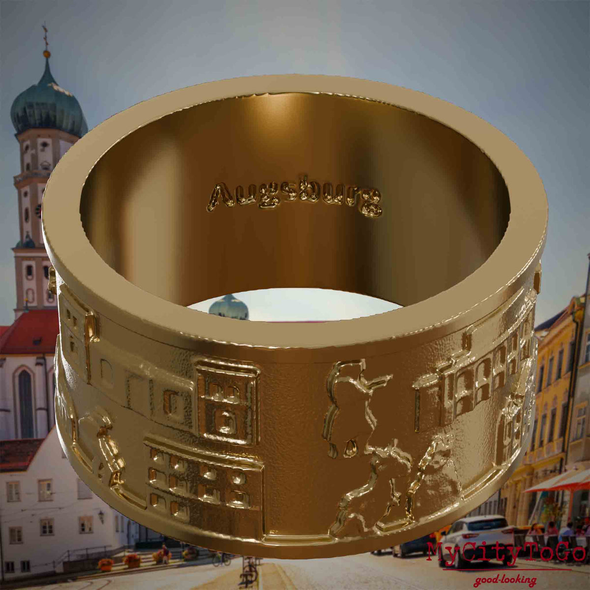 Ring aus vergoldetem Edelstahl mit Reliefs bekannter Sehenswürdigkeiten der Stadt Augsburg und einer Gravur des Stadtnamens auf der Innenseite. Den Hintergrund bildet eine Ansicht der Stadt Augsburg.