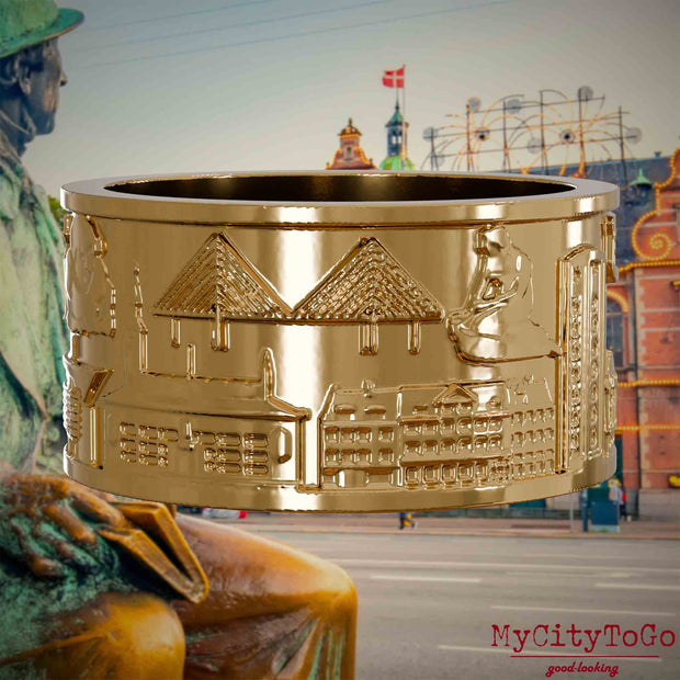Vergoldeter Ring mit Reliefs bekannter Sehenswürdigkeiten der Stadt Kopenhagen. Den Hintergrund bildet eine 
Ansicht der Stadt Kopenhagen.