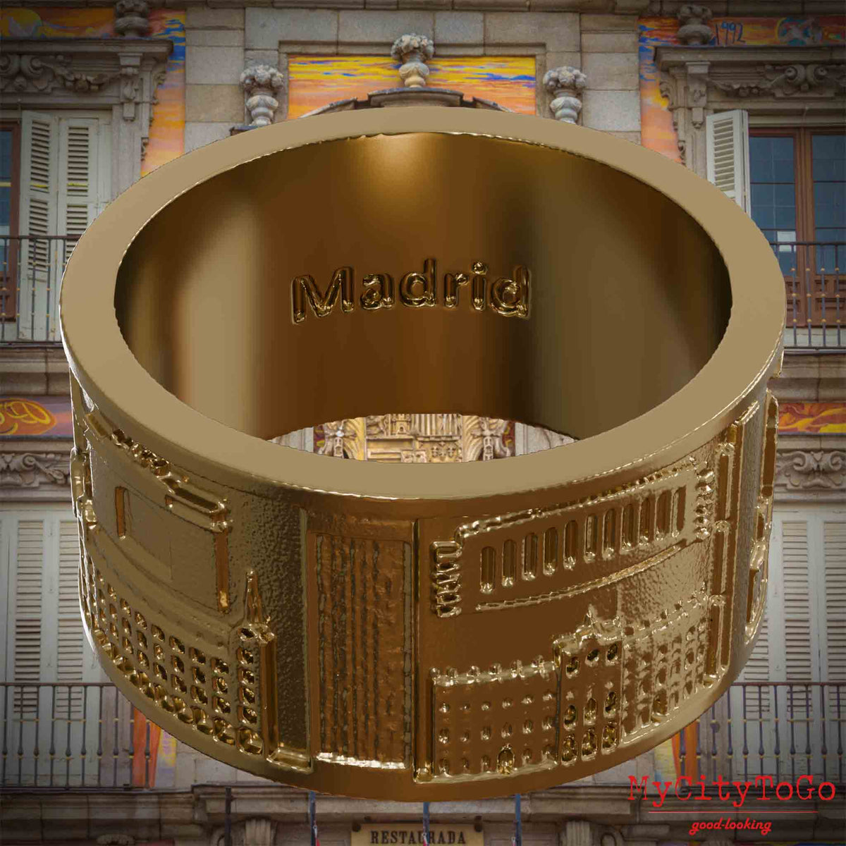 Ring aus vergoldetem Edelstahl mit Reliefs bekannter Sehenswürdigkeiten der Stadt Madrid und einer Gravur des Stadtnamens auf der Innenseite. Den Hintergrund bildet eine Ansicht der Stadt Madrid.