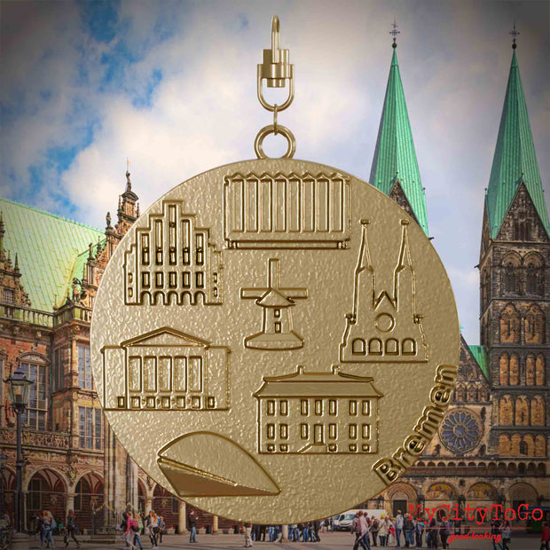 Halskette mit Drehwirbel und Rückseite eines Schmuckanhängers aus vergoldetem Edelstahl, auf dem Reliefs bekannter Sehenswürdigkeiten der Stadt Bremen abgebildet sind. Den Hintergrund bildet eine Ansicht der Stadt Bremen.
