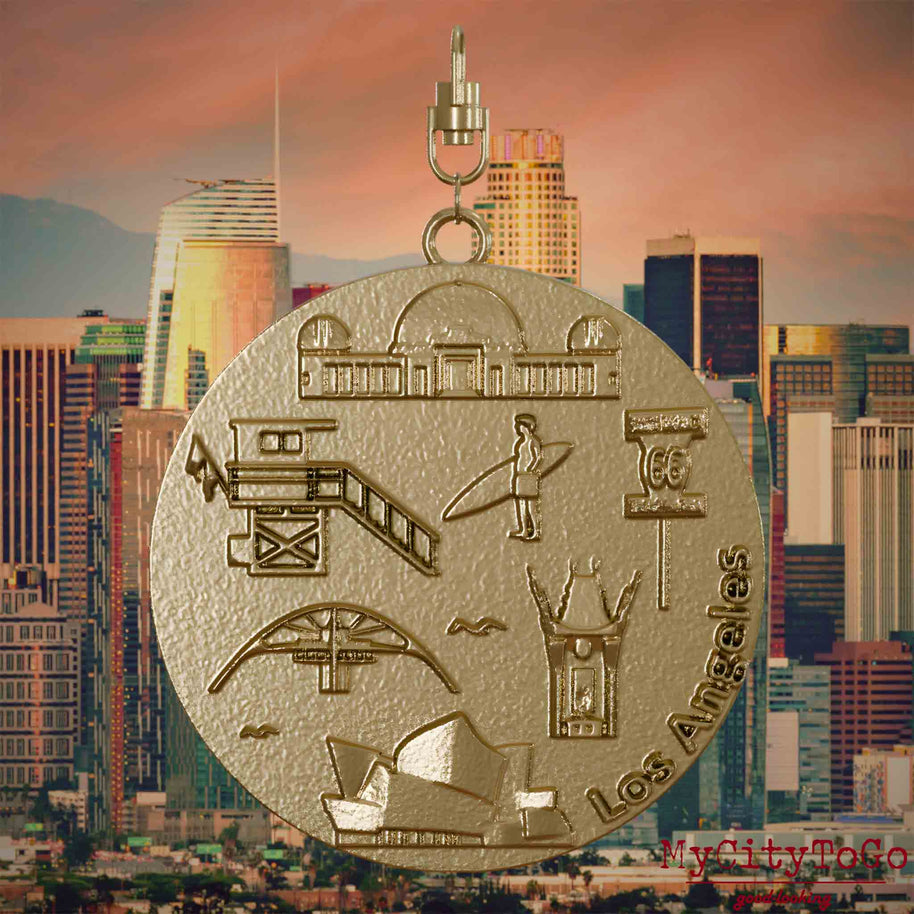 Halskette mit Drehwirbel und Rückseite eines Schmuckanhängers aus vergoldetem Edelstahl, auf dem Reliefs bekannter Sehenswürdigkeiten der Stadt Los Angeles abgebildet sind. Den Hintergrund bildet eine Ansicht der Stadt Los Angeles.
