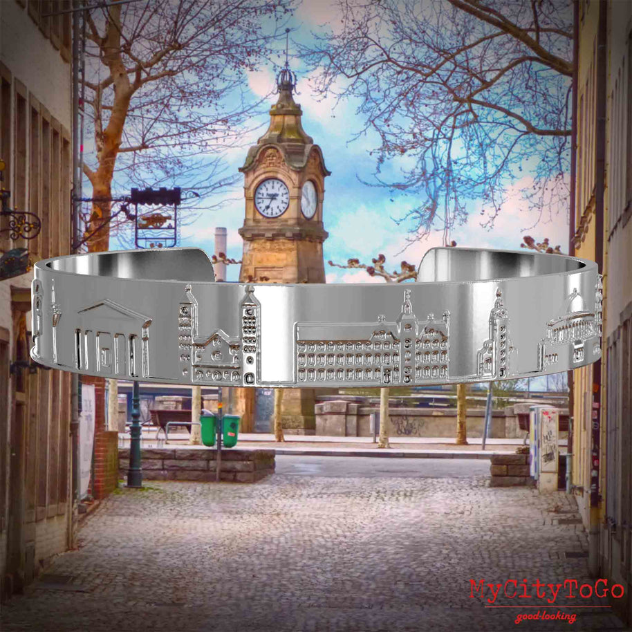 Versilberter Armreif mit Reliefs bekannter Sehenswürdigkeiten der Stadt Duesseldorf. Den Hintergrund bildet eine Ansicht der Stadt Duesseldorf.