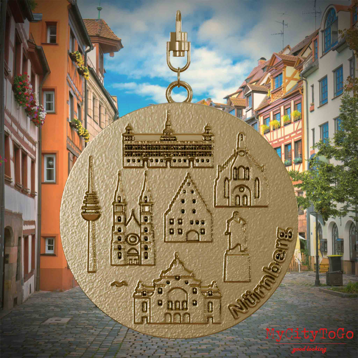 Halskette mit Drehwirbel und Vorderseite eines Schmuckanhängers aus vergoldetem Edelstahl, auf dem Reliefs bekannter Sehenswürdigkeiten der Stadt Nuernberg abgebildet sind. Den Hintergrund bildet eine Ansicht der Stadt Nuernberg.