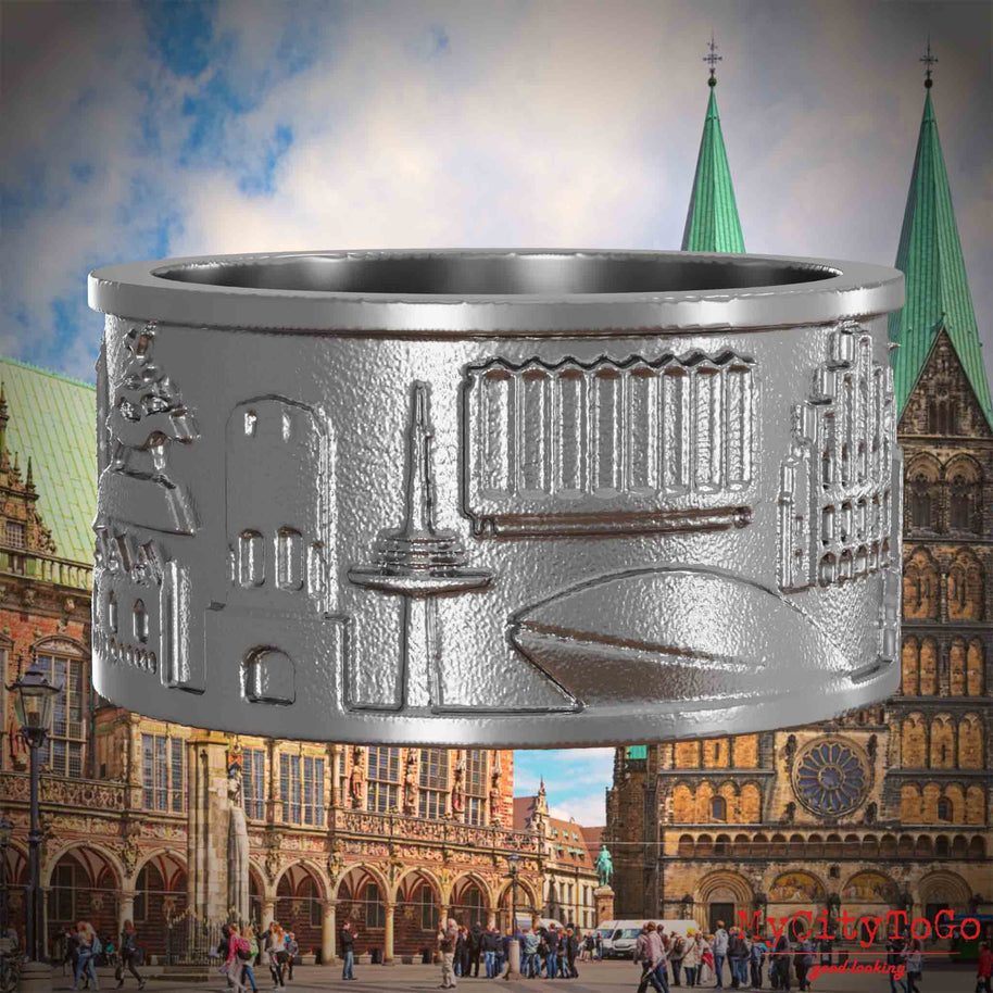 Ring aus Edelstahl mit Reliefs bekannter Sehenswürdigkeiten der Stadt Bremen. Den Hintergrund bildet eine Ansicht der Stadt Bremen.