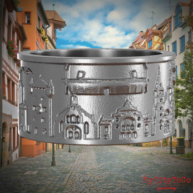 Ring aus Edelstahl mit Reliefs bekannter Sehenswürdigkeiten der Stadt Nuernberg. Den Hintergrund bildet eine Ansicht der Stadt  Nuernberg.