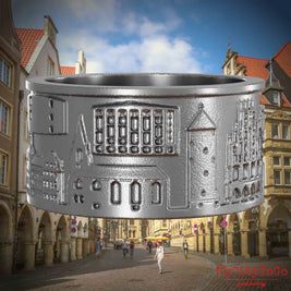 Ring aus Edelstahl mit Reliefs bekannter Sehenswürdigkeiten der Stadt Muenster. Den Hintergrund bildet eine Ansicht der Stadt Muenster.