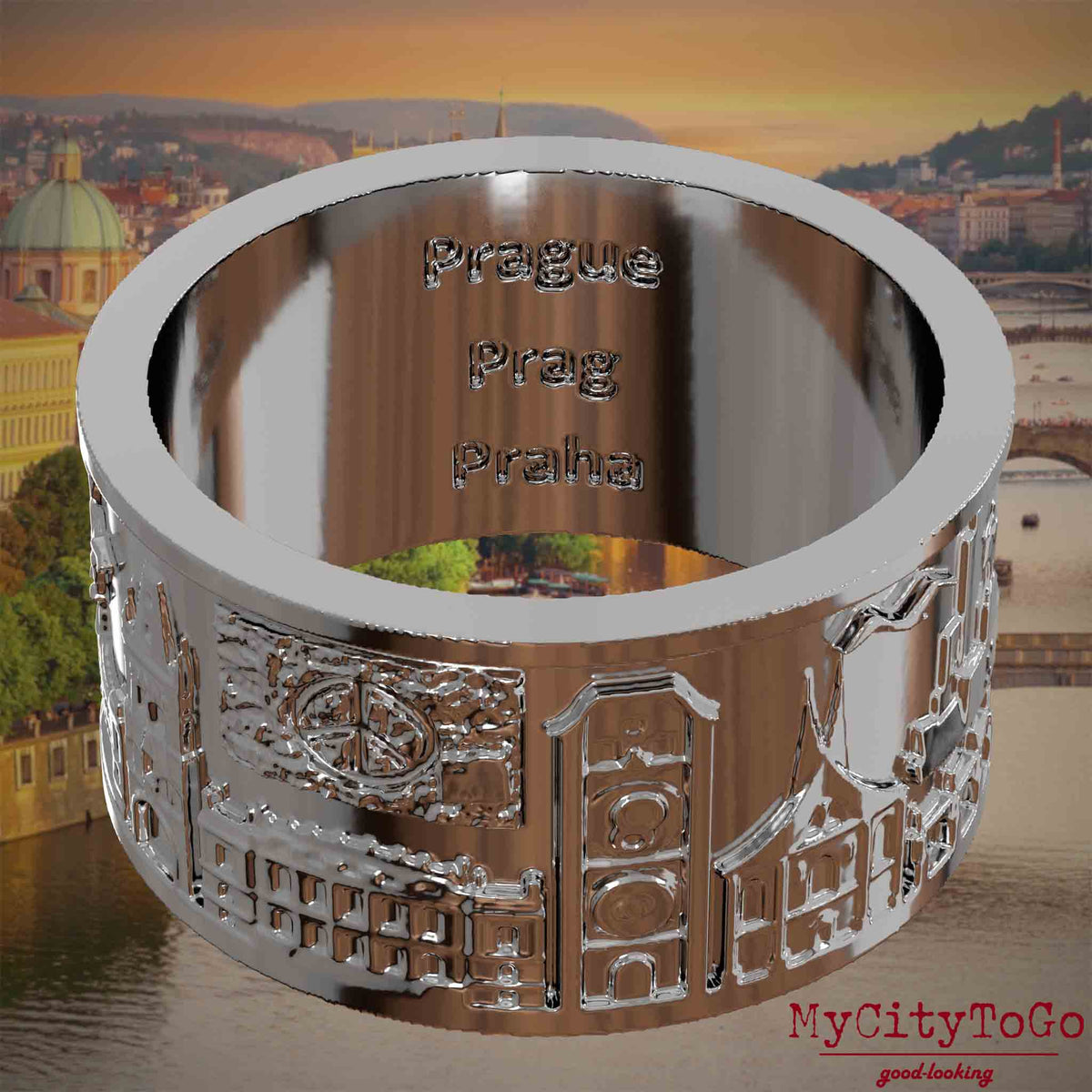 Versilberter Ring mit Reliefs bekannter Sehenswürdigkeiten der Stadt Prag und einer Gravur des Stadtnamens auf der Innenseite. Den Hintergrund bildet eine Ansicht der Stadt Prag.