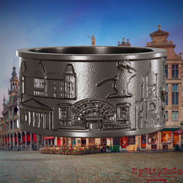 Ring aus Titan mit Reliefs bekannter Sehenswürdigkeiten der Stadt Bruessel. Den Hintergrund bildet eine Ansicht der Stadt Bruessel.