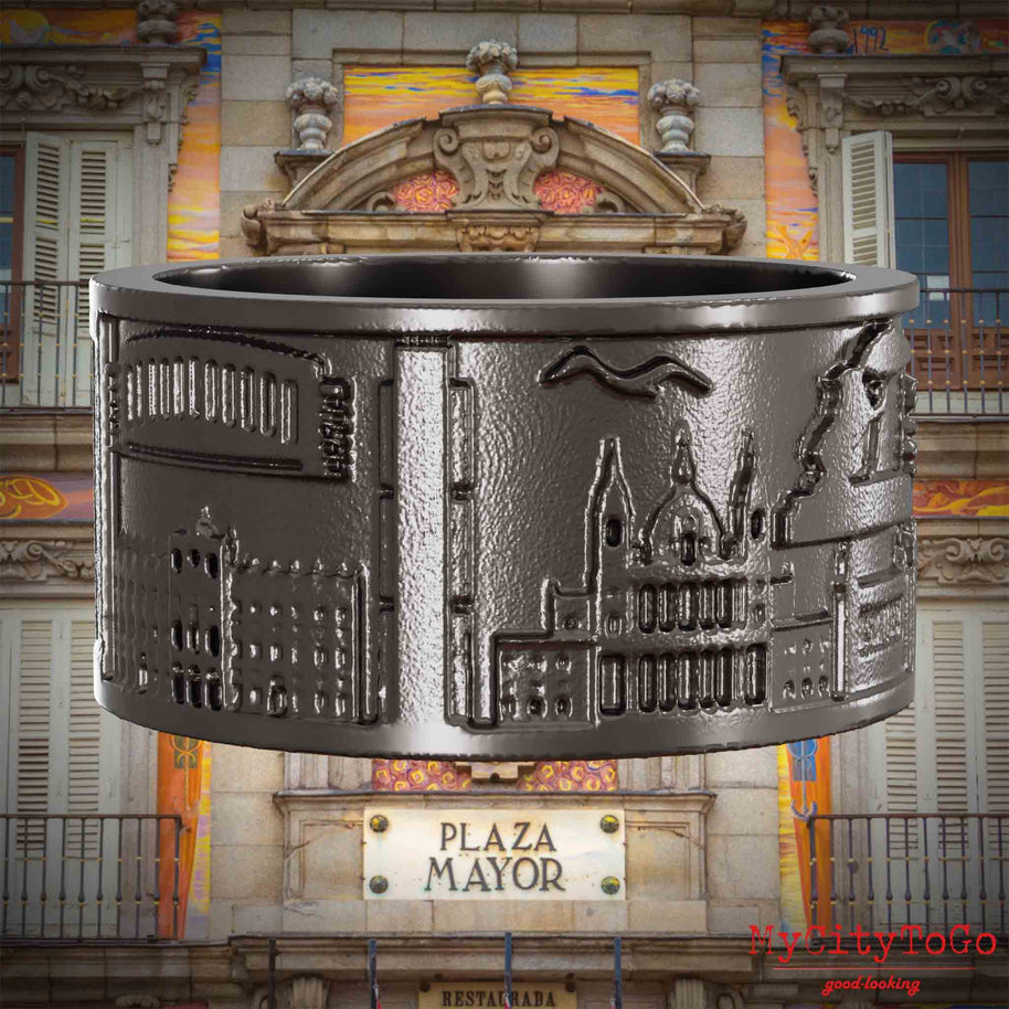 Ring aus Titan mit Reliefs bekannter Sehenswürdigkeiten der Stadt Madrid. Den Hintergrund bildet eine Ansicht der Stadt Madrid.