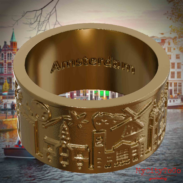 Ring aus vergoldetem Edelstahl mit Reliefs bekannter Sehenswürdigkeiten der Stadt Amsterdam und einer Gravur des Stadtnamens auf der Innenseite. Den Hintergrund bildet eine Ansicht der Stadt Amsterdam.
