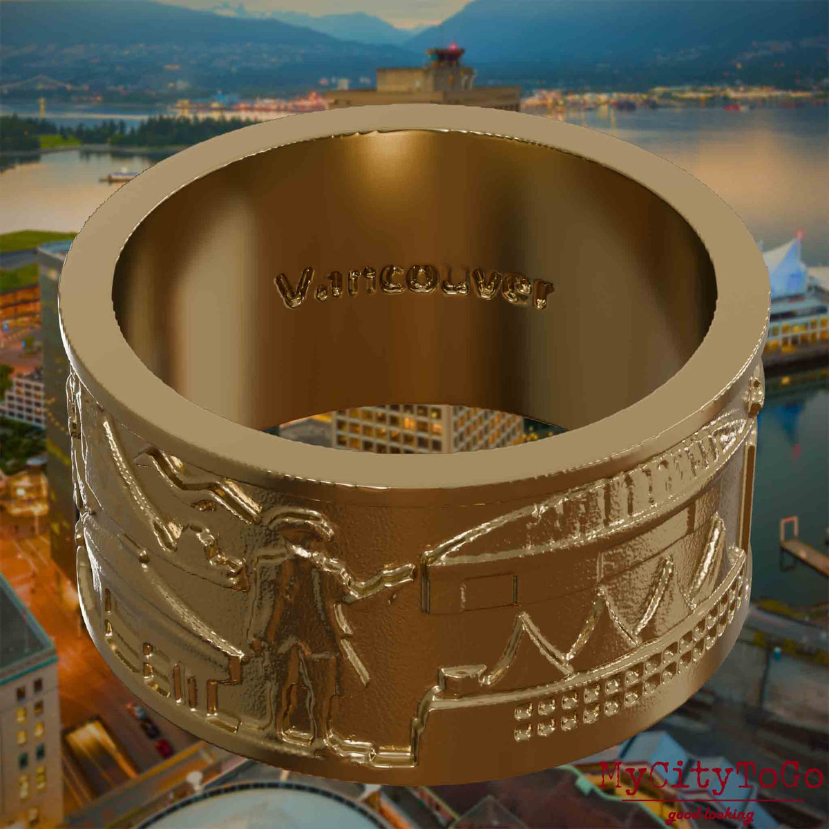 Vergoldeter Ring aus Edelstahl mit Reliefs bekannter Sehenswürdigkeiten der Stadt Vanouver und einer Gravur des Stadtnamens auf der Innenseite. Den Hintergrund bildet eine Ansicht der Stadt Vancouver.