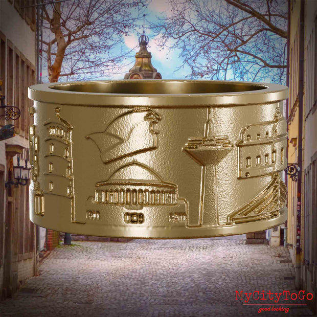 Ring aus vergoldetem Edelstahl mit Reliefs bekannter Sehenswürdigkeiten der Stadt Duesseldorf. Den Hintergrund bildet eine Ansicht der Stadt Duesseldorf.