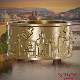 Ring aus vergoldetem Edelstahl mit Reliefs bekannter Sehenswürdigkeiten der Stadt Prag. Den Hintergrund bildet eine Ansicht der Stadt Prag.