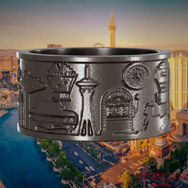Ring aus Titan mit Reliefs bekannter Sehenswürdigkeiten der Stadt Las Vegas. Den Hintergrund bildet eine Ansicht der Stadt Las Vegas.