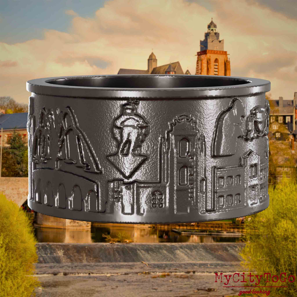 Ring aus Titan mit Reliefs bekannter Sehenswürdigkeiten der Stadt Wetzlar. Den Hintergrund bildet eine Ansicht der Stadt Wetzlar.