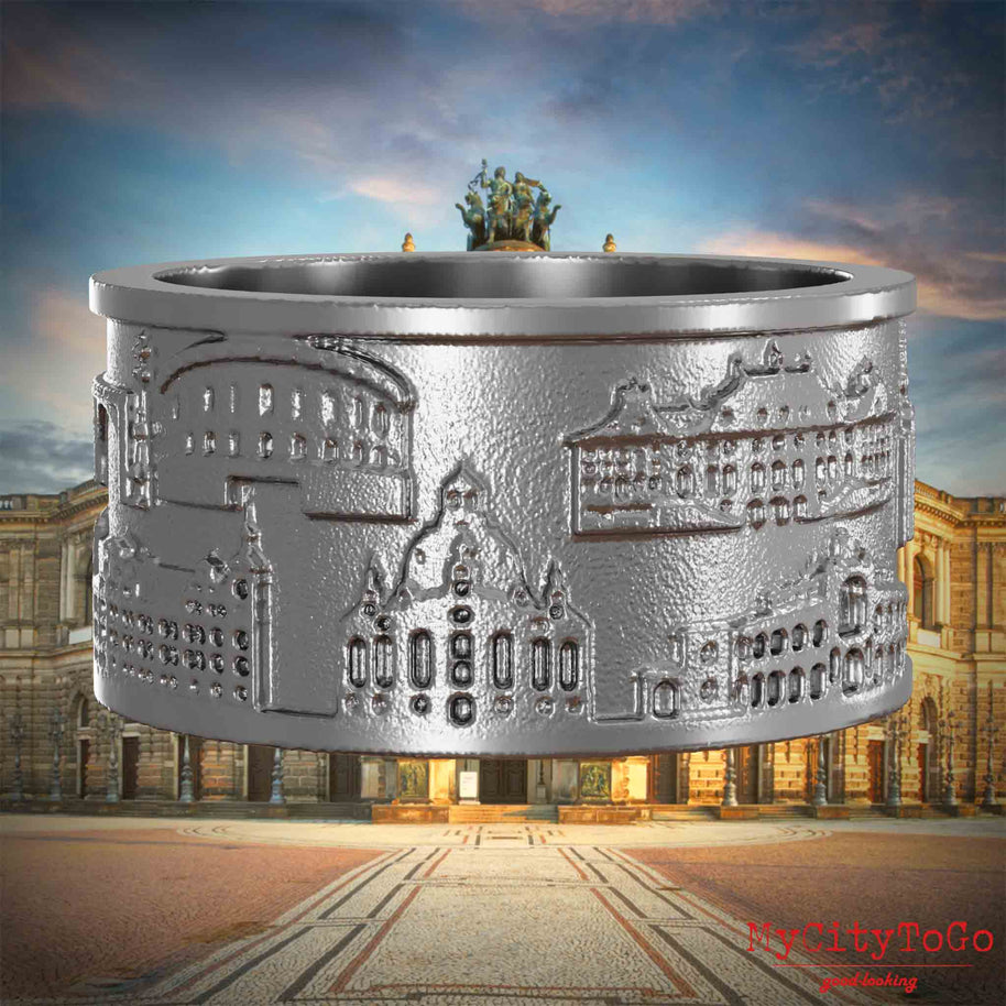Ring aus Edelstahl mit Reliefs bekannter Sehenswürdigkeiten der Stadt Dresden. Den Hintergrund bildet eine Ansicht der Stadt Dresden.
