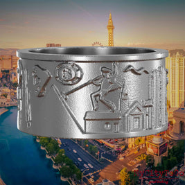 Ring aus Edelstahl mit Reliefs bekannter Sehenswürdigkeiten der Stadt Las Vegas. Den Hintergrund bildet eine Ansicht der Stadt Las Vegas.
