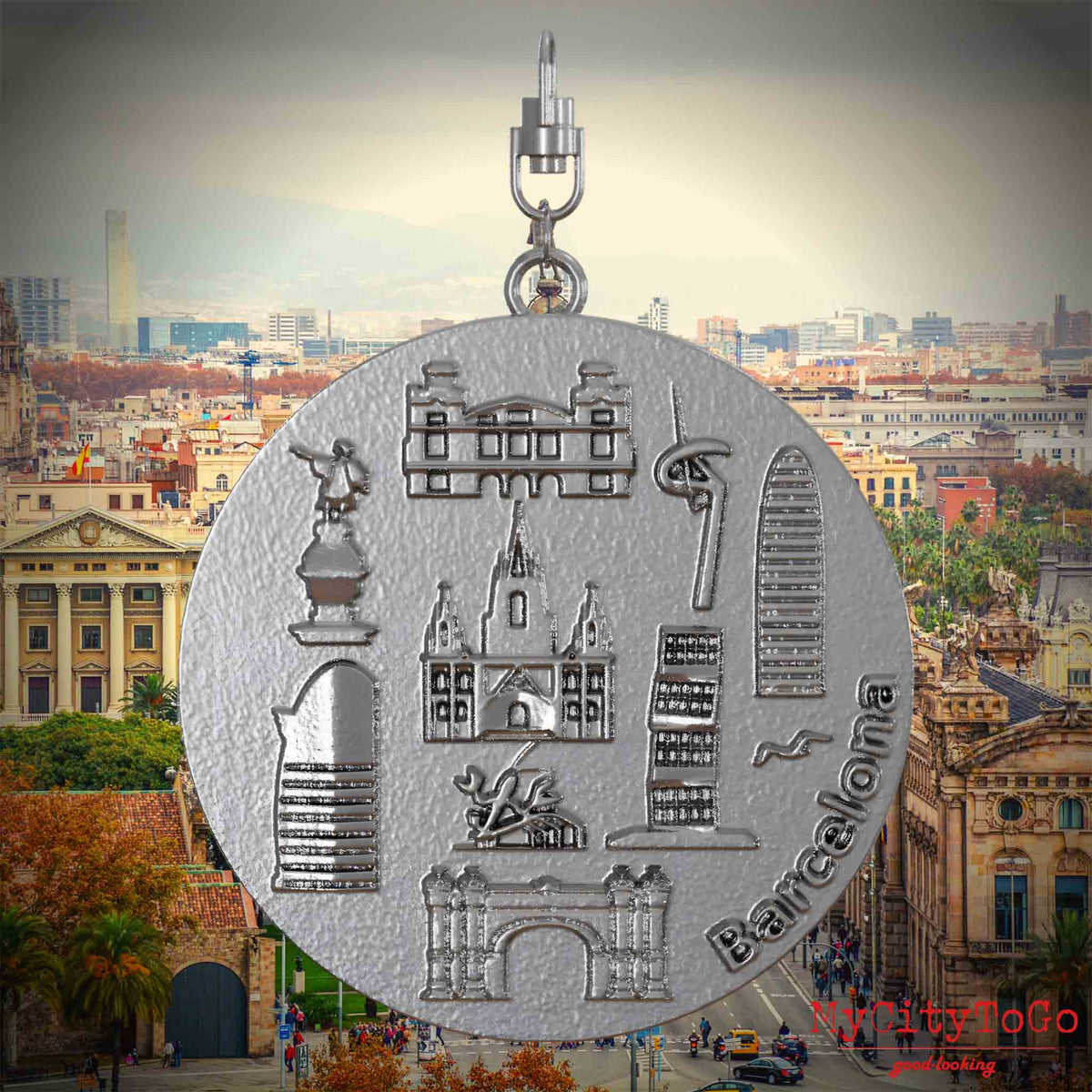 Halskette mit Drehwirbel und Vorderseite eines Schmuckanhängers aus Edelstahl, auf dem Reliefs bekannter Sehenswürdigkeiten der Stadt Barcelona abgebildet sind. Den Hintergrund bildet eine Ansicht der Stadt Barcelona.
