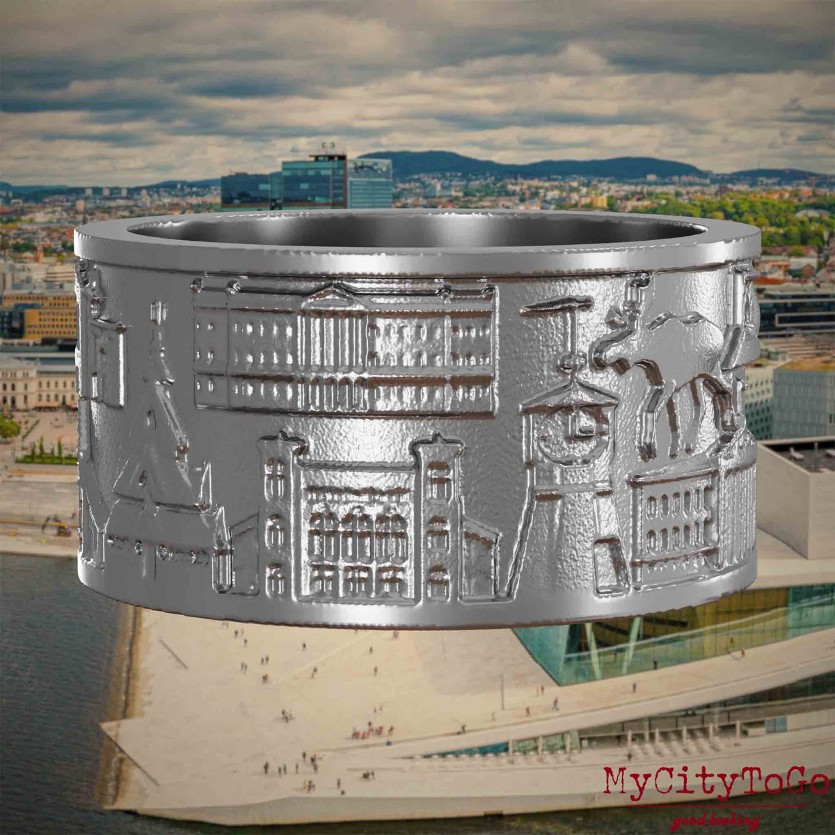 Ring aus Edelstahl mit Reliefs bekannter Sehenswürdigkeiten der Stadt Oslo. Den Hintergrund bildet eine Ansicht der Stadt Oslo.