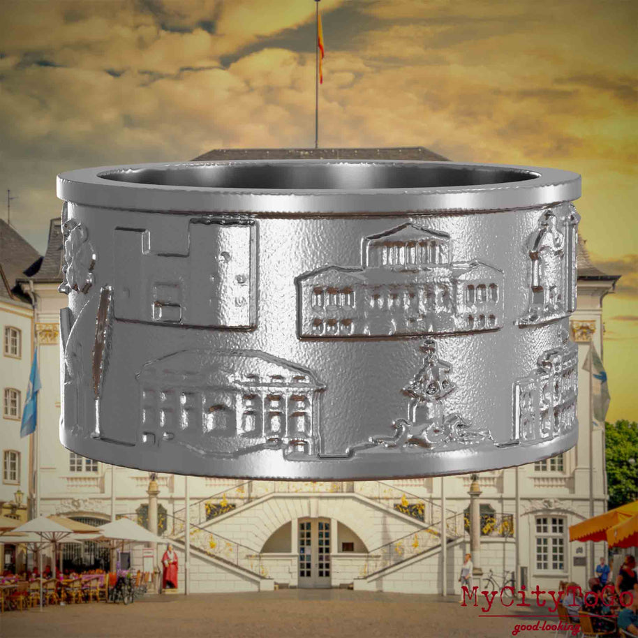 Ring aus Edelstahl mit Reliefs bekannter Sehenswürdigkeiten der Stadt Bonn. Den Hintergrund bildet eine Ansicht der Stadt Bonn.