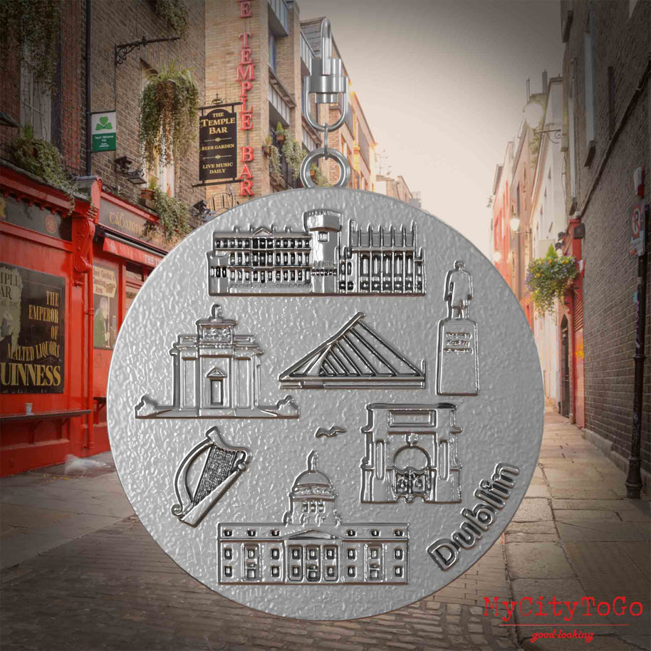 Halskette mit Drehwirbel und Rückseite eines Schmuckanhängers aus Edelstahl, auf dem Reliefs bekannter Sehenswürdigkeiten der Stadt Dublin abgebildet sind. Den Hintergrund bildet eine Ansicht der Stadt Dublin.

