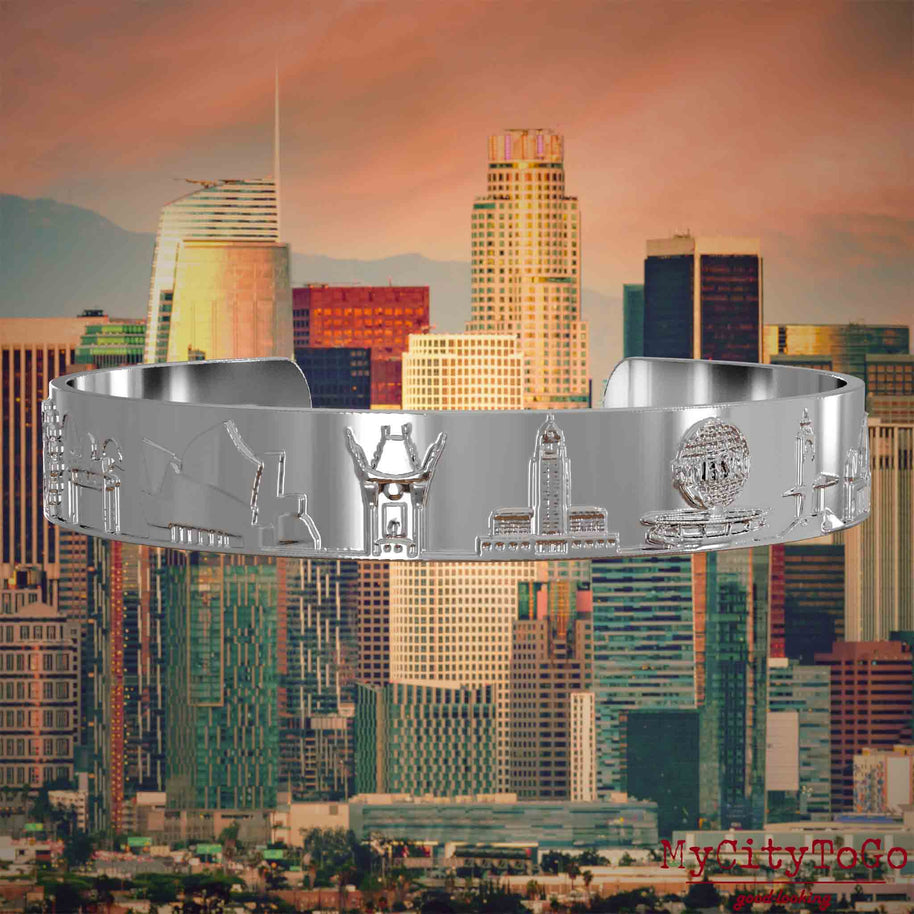 Versilberter Armreif mit Reliefs bekannter Sehenswürdigkeiten der Stadt Los Angeles. Den Hintergrund bildet eine Ansicht der Stadt Los Angeles.