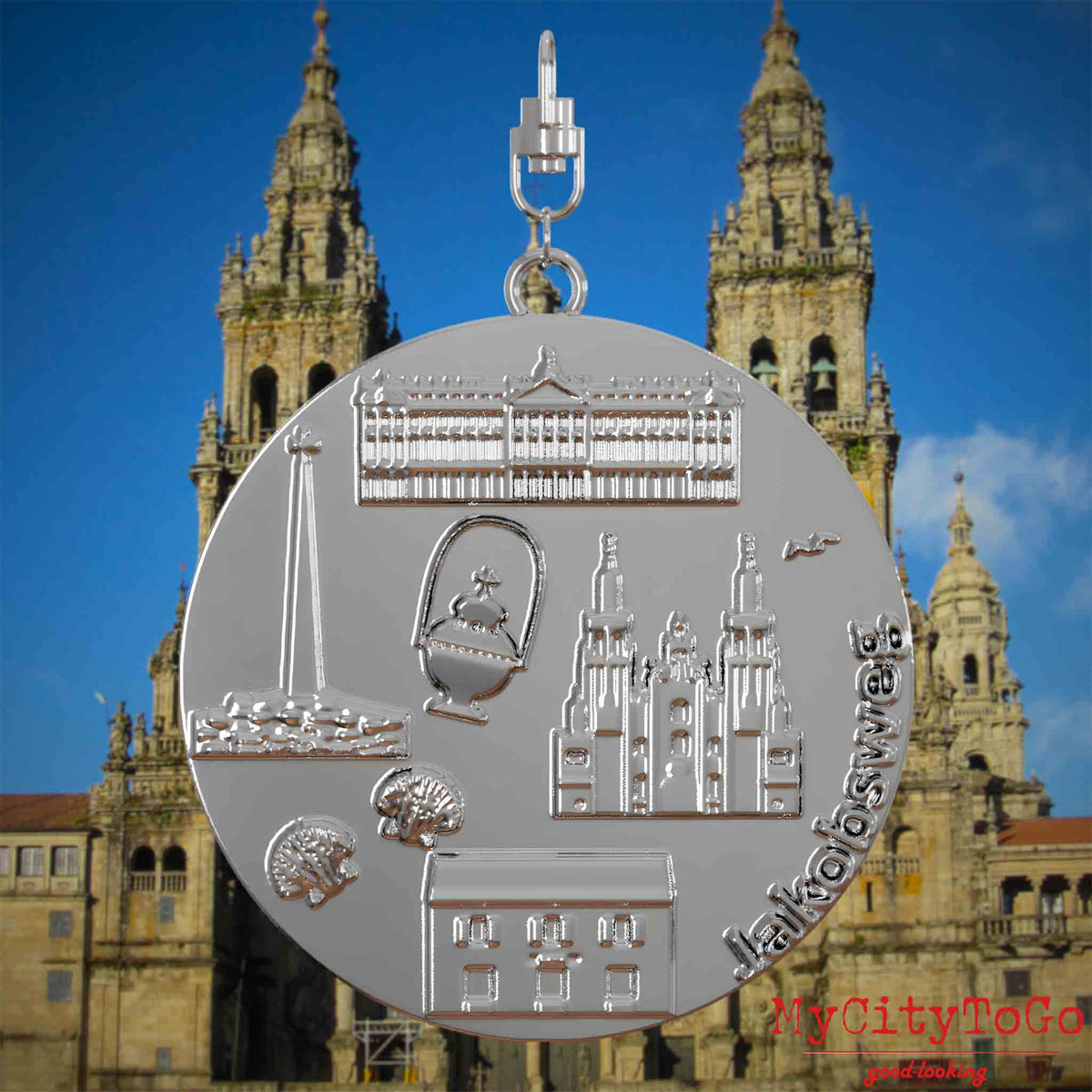 Halskette mit Drehwirbel und Rückseite eines silbernen Schmuckanhängers, auf dem Reliefs bekannter Sehenswürdigkeiten des Jakobwegs abgebildet sind. Den Hintergrund bildet eine Ansicht der Stadt Santiago de Compostela.
