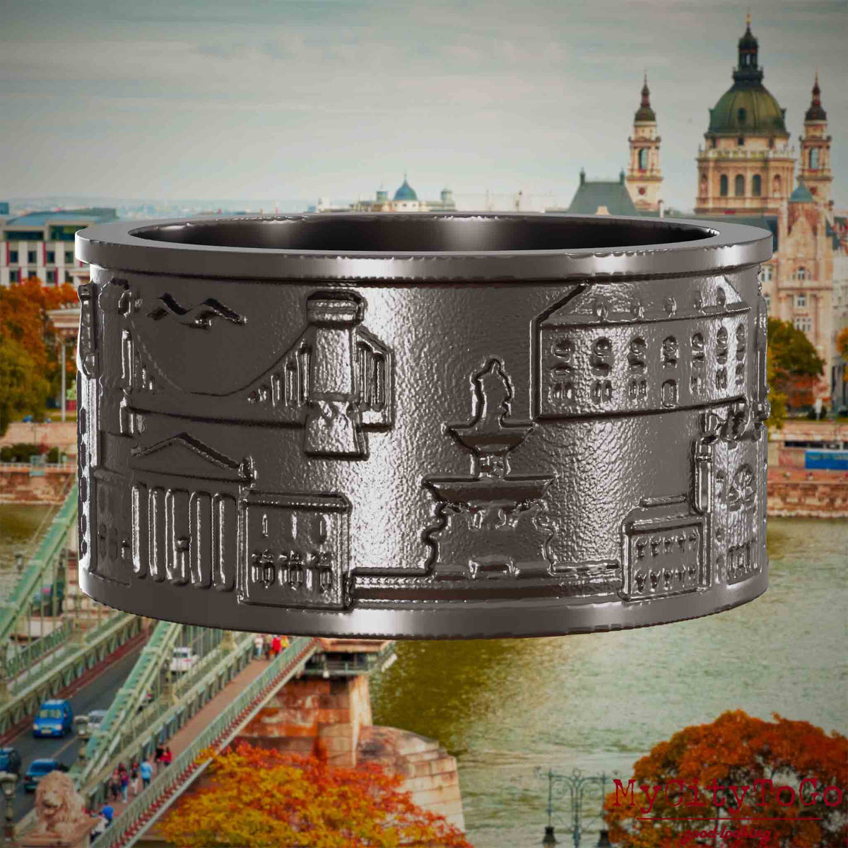 Ring aus Titan mit Reliefs bekannter Sehenswürdigkeiten der Stadt Budapest. Den Hintergrund bildet eine Ansicht der Stadt Budapest.