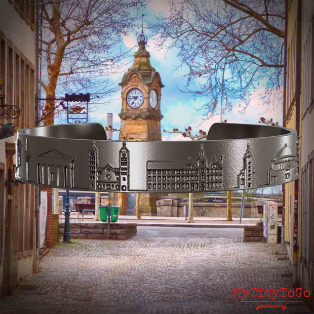 Armreif aus Titan mit Reliefs bekannter Sehenswürdigkeiten der Stadt Duesseldorf. Den Hintergrund bildet eine Ansicht der Stadt Duesseldorf.