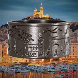 Ring aus Titan mit Reliefs bekannter Sehenswürdigkeiten der Stadt Marseille. Den Hintergrund bildet eine Ansicht der Stadt Marseille.