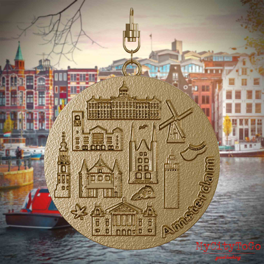Halskette mit Drehwirbel und Rückseite eines Schmuckanhängers aus vergoldetem Edelstahl, auf dem Reliefs bekannter Sehenswürdigkeiten der Stadt Amsterdam abgebildet sind. Den Hintergrund bildet eine Ansicht der Stadt Amsterdam.
