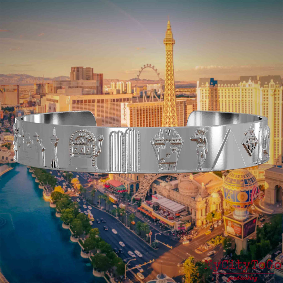 Versilberter Armreif mit Reliefs bekannter Sehenswürdigkeiten der Stadt Las Vegas. Den Hintergrund bildet eine Ansicht der Stadt Las Vegas.