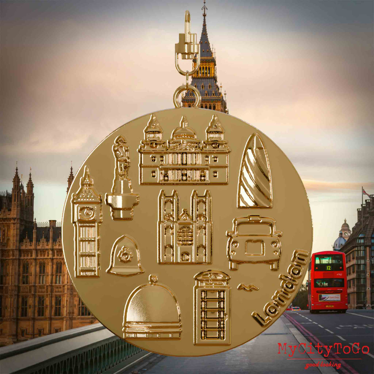 Halskette mit Drehwirbel und Rückseite eines vergoldeten Schmuckanhängers, auf dem Reliefs bekannter Sehenswürdigkeiten der Stadt London abgebildet sind. Den Hintergrund bildet eine Ansicht der Stadt London.
