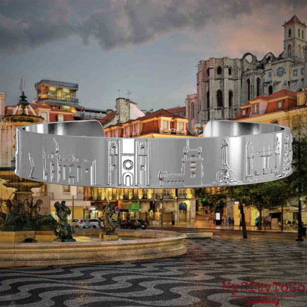 Silberner Armreif mit Reliefs bekannter Sehenswürdigkeiten der Stadt Lissabon. Den Hintergrund bildet eine Ansicht der Stadt Lissabon.