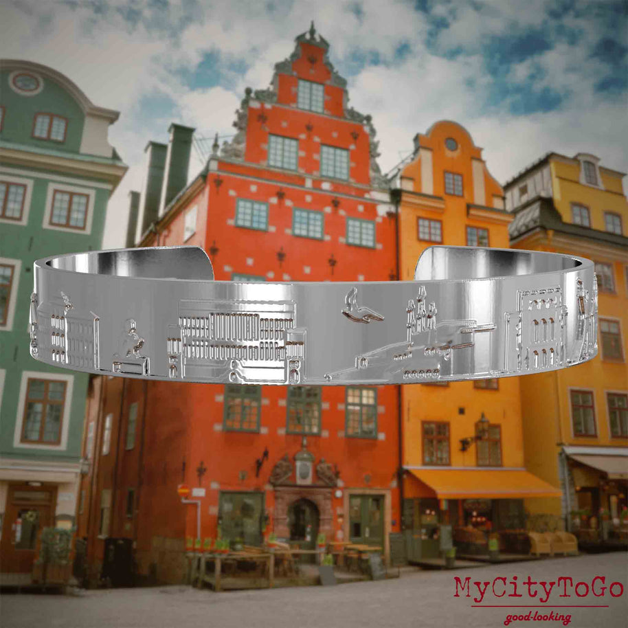 Versilberter Armreif mit Reliefs bekannter Sehenswürdigkeiten der Stadt Stockholm. Den Hintergrund bildet eine Ansicht der Stadt Stockholm.