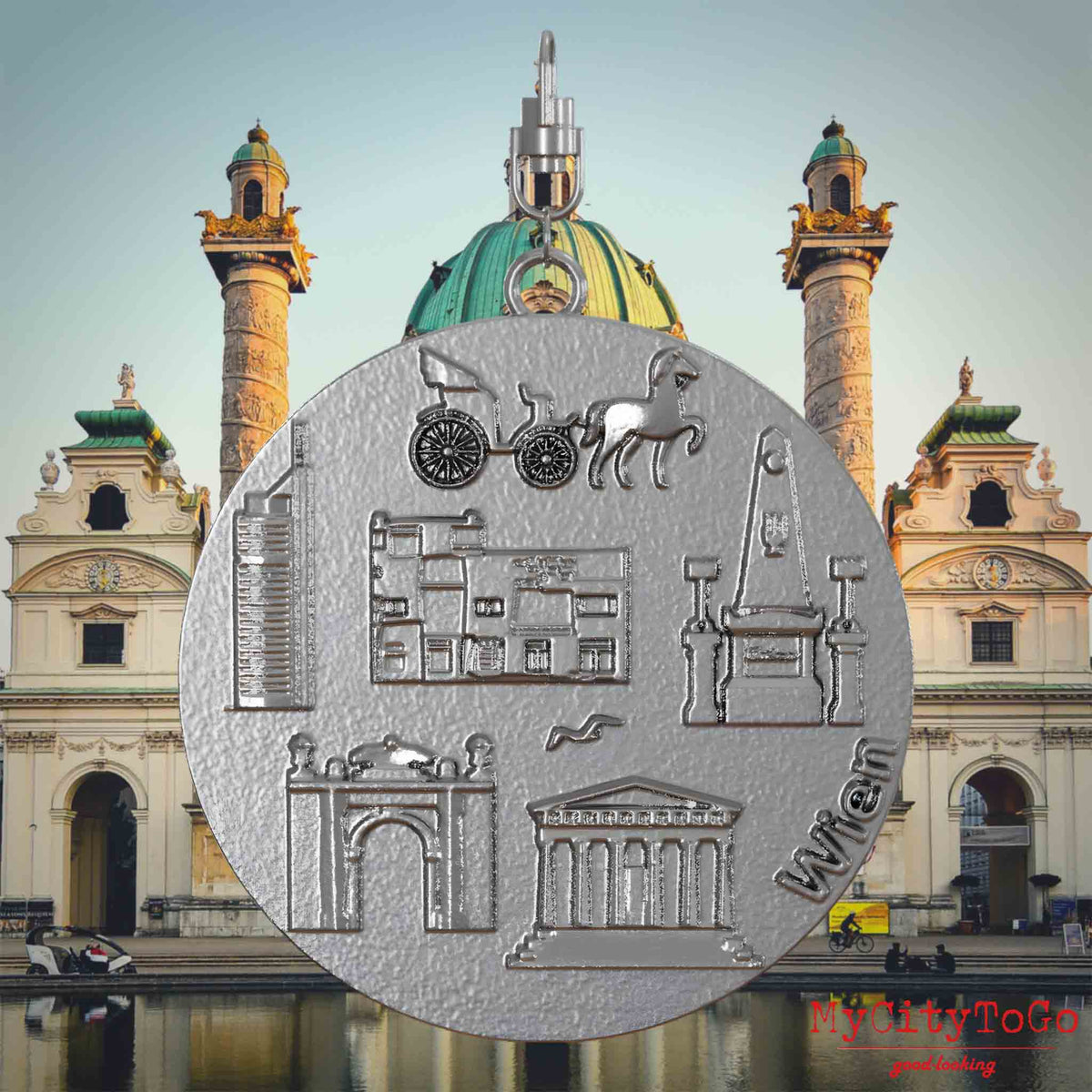 Halskette mit Drehwirbel und Vorderseite eines Schmuckanhängers aus Edelstahl, auf dem Reliefs bekannter Sehenswürdigkeiten der Stadt Wien abgebildet sind. Den Hintergrund bildet eine Ansicht der Stadt Wien.
