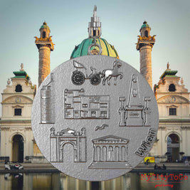 Halskette mit Drehwirbel und Vorderseite eines Schmuckanhängers aus Edelstahl, auf dem Reliefs bekannter Sehenswürdigkeiten der Stadt Wien abgebildet sind. Den Hintergrund bildet eine Ansicht der Stadt Wien.
