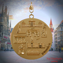 Halskette mit Drehwirbel und Rückseite eines vergoldeten Schmuckanhängers, auf dem Reliefs bekannter Sehenswürdigkeiten der Stadt Muenchen abgebildet sind. Den Hintergrund bildet eine Ansicht der Stadt Muenchen.