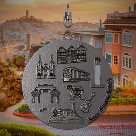 Halskette mit Drehwirbel und Rückseite eines Schmuckanhängers aus Titan, auf dem Reliefs bekannter Sehenswürdigkeiten der Stadt San Francisco abgebildet sind. Den Hintergrund bildet eine Ansicht der Stadt San Francisco.

