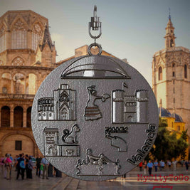 Halskette mit Drehwirbel und Rückseite eines Schmuckanhängers aus Titan, auf dem Reliefs bekannter Sehenswürdigkeiten der Stadt Valencia abgebildet sind. Den Hintergrund bildet eine Ansicht der Stadt Valencia.
