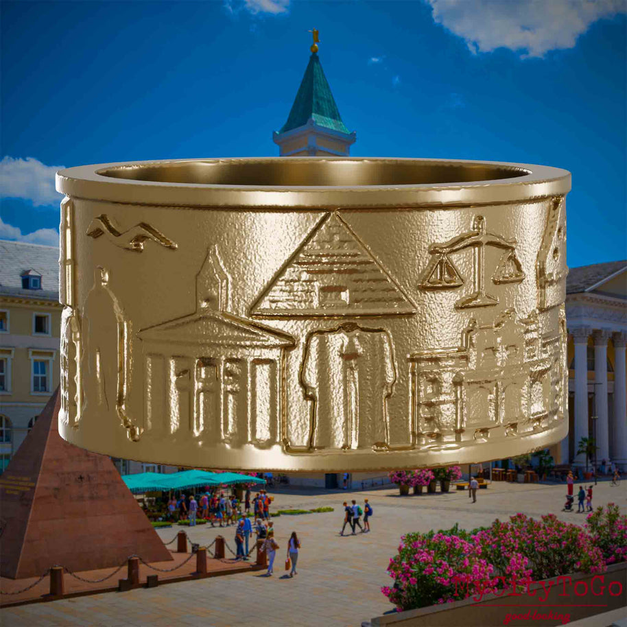 Ring aus vergoldetem Edelstahl mit Reliefs bekannter Sehenswürdigkeiten der Stadt Karlsruhe. Den Hintergrund bildet eine Ansicht der Stadt Karlsruhe.