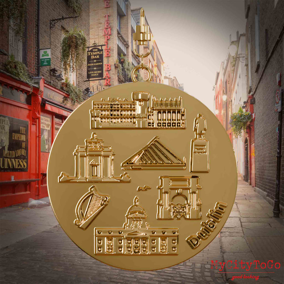 Halskette mit Drehwirbel und Rückseite eines vergoldeten Schmuckanhängers, auf dem Reliefs bekannter Sehenswürdigkeiten der Stadt Dublin abgebildet sind. Den Hintergrund bildet eine Ansicht der Stadt Dublin.
