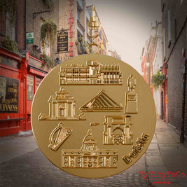 Halskette mit Drehwirbel und Rückseite eines vergoldeten Schmuckanhängers, auf dem Reliefs bekannter Sehenswürdigkeiten der Stadt Dublin abgebildet sind. Den Hintergrund bildet eine Ansicht der Stadt Dublin.
