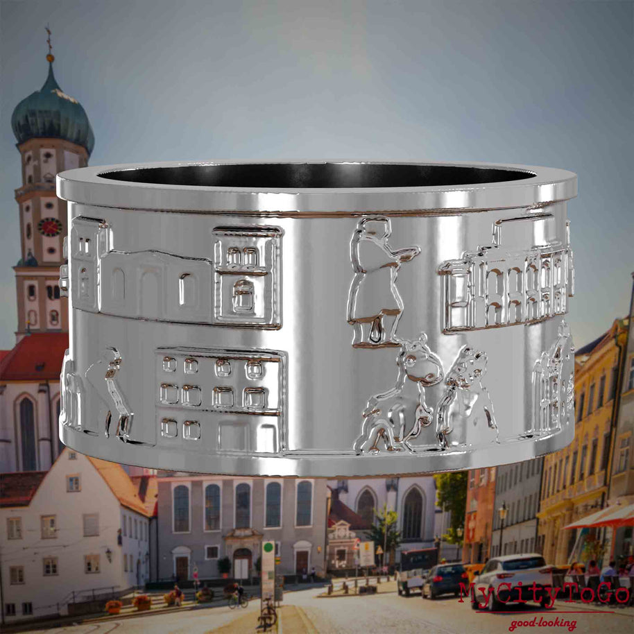 Silberner Ring mit Reliefs bekannter Sehenswürdigkeiten der Stadt Augsburg. Den Hintergrund bildet eine Ansicht der Stadt Augsburg.