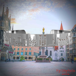 Versilberter Armreif mit Reliefs bekannter Sehenswürdigkeiten der Stadt München. Den Hintergrund bildet eine Ansicht der Stadt Muenchen.