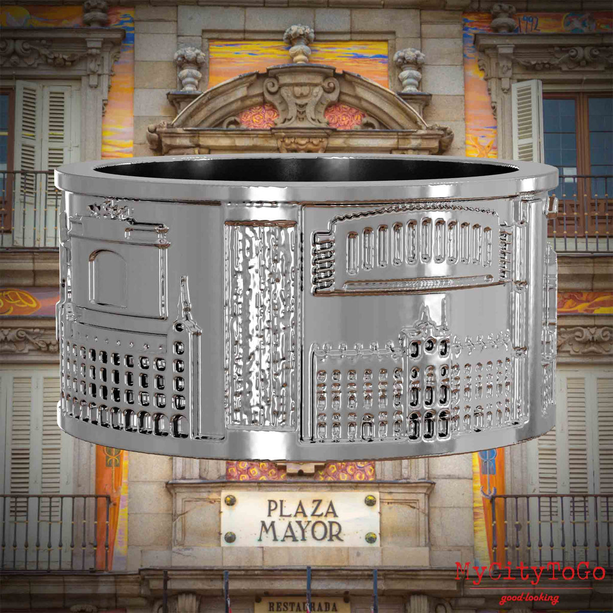 Silberner Ring mit Reliefs bekannter Sehenswürdigkeiten der Stadt Madrid. Den Hintergrund bildet eine Ansicht der Stadt Madrid.