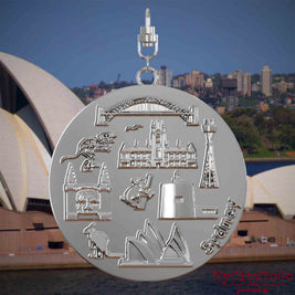 Halskette mit Drehwirbel und Vorderseite eines silbernen Schmuckanhängers, auf dem Reliefs bekannter Sehenswürdigkeiten der Stadt Sydney abgebildet sind. Den Hintergrund bildet eine Ansicht der Stadt Sydney.
